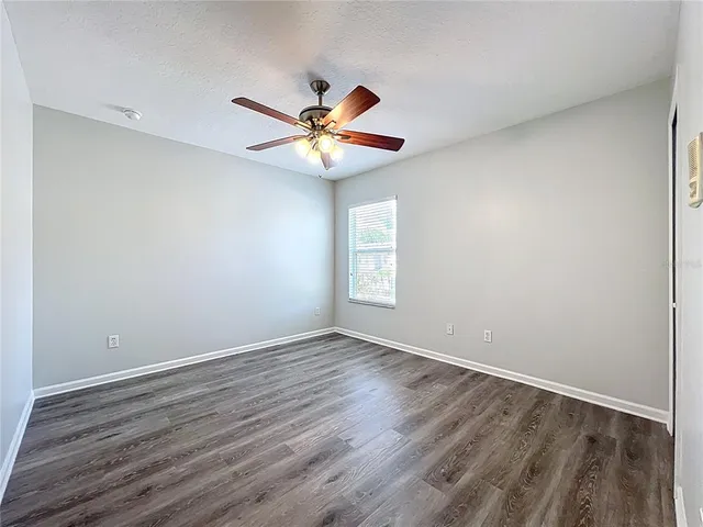 an empty room with wooden floor fan and windows