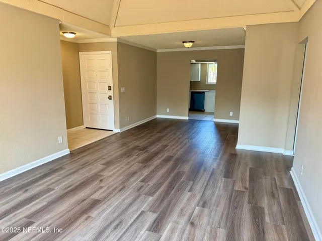 a view of a room that has a bed and wooden floor