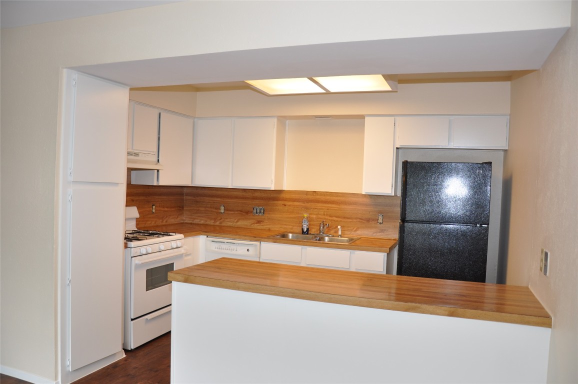 10810 Topperwein Drive, Unit C Austin, TX 78758 - Photo 2 of 11 Kitchen featuring white appliances, a sink, under cabinet range hood, and white cabinetry