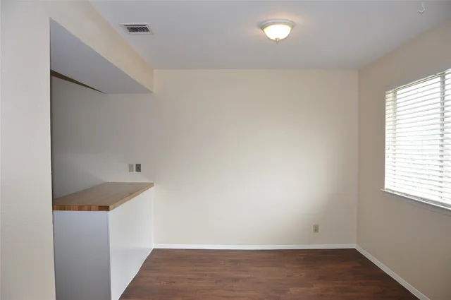 an empty room with wooden floor and window