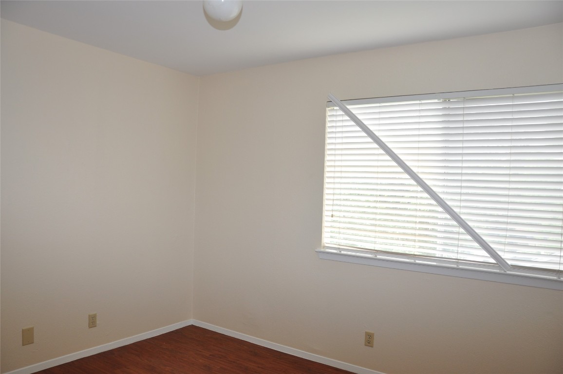 10810 Topperwein Drive, Unit C Austin, TX 78758 - Photo 7 of 11 Unfurnished room featuring dark wood-style floors and baseboards