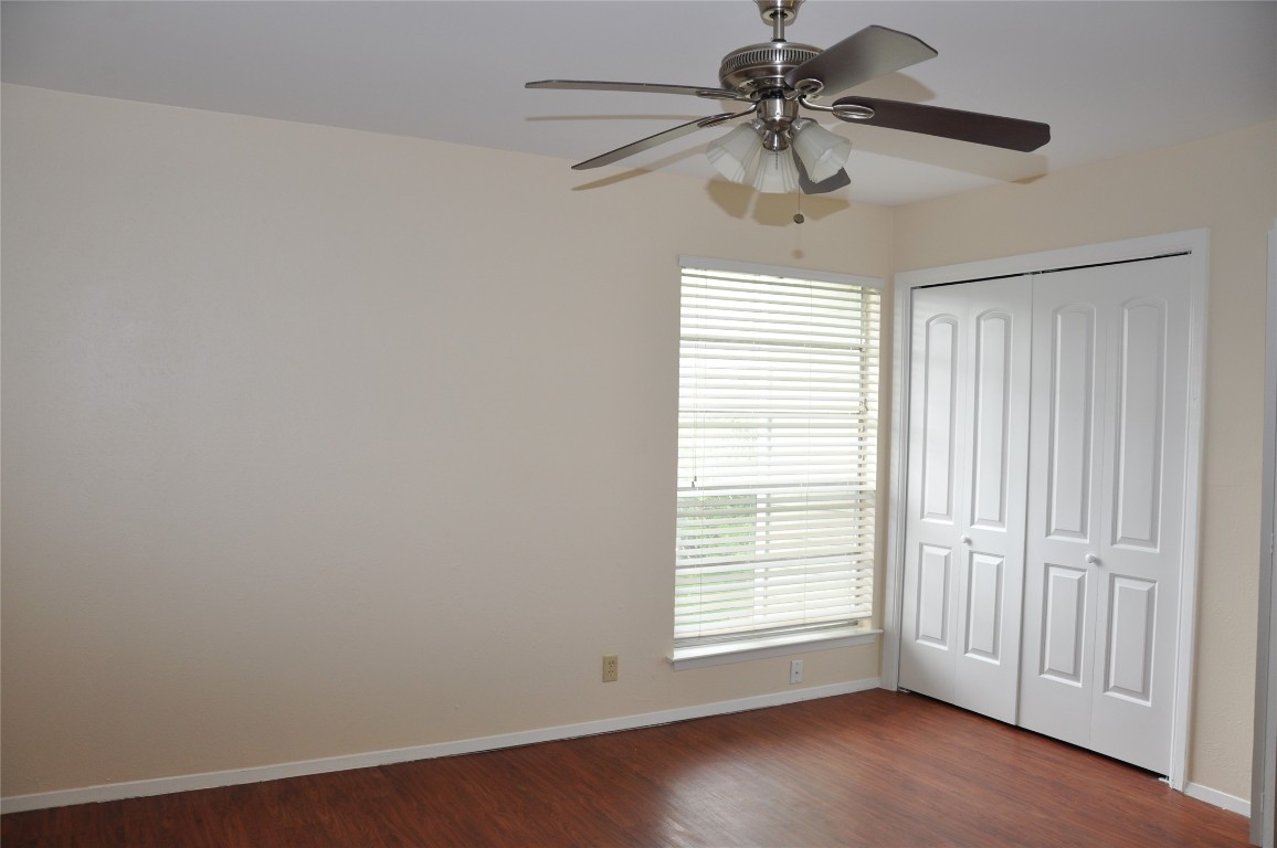 10810 Topperwein Drive, Unit C Austin, TX 78758 - Photo 8 of 11 Unfurnished bedroom with dark wood-style flooring, baseboards, a closet, and ceiling fan