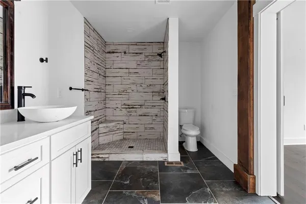 a bathroom with a granite countertop sink a toilet and shower
