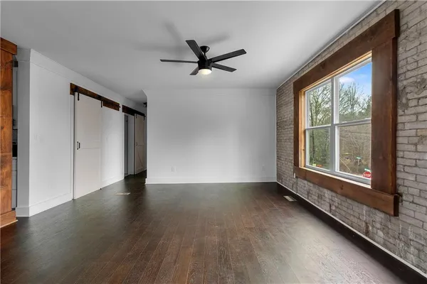 a view of an empty room with a window and wooden floor