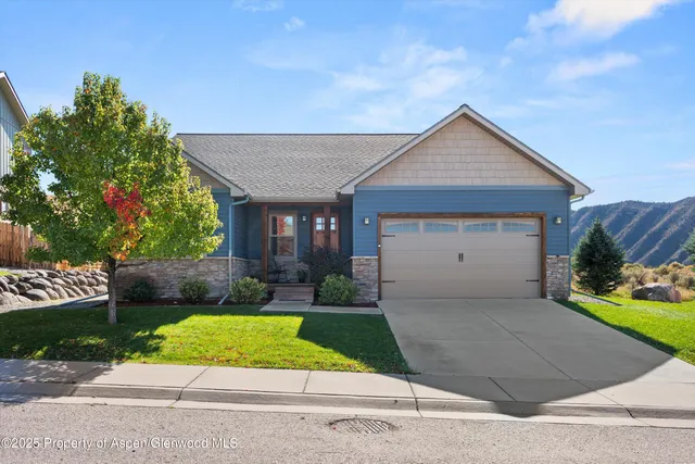 a view of a house with a yard plants and a large tree