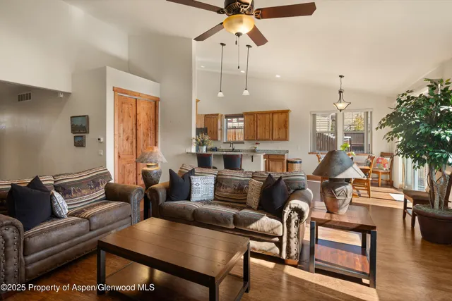 a living room with furniture kitchen view and a chandelier