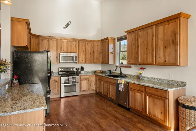 a kitchen with stainless steel appliances granite countertop wooden cabinets a stove top oven a sink and dishwasher