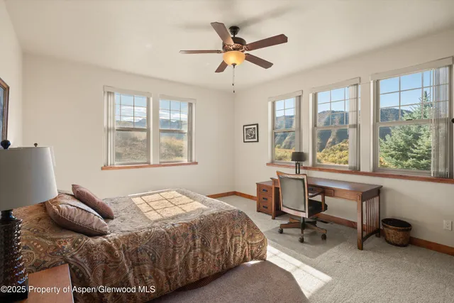 a bedroom with a bed a table and a large window