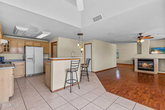 a kitchen with stainless steel appliances kitchen island a table chairs in it and wooden floors