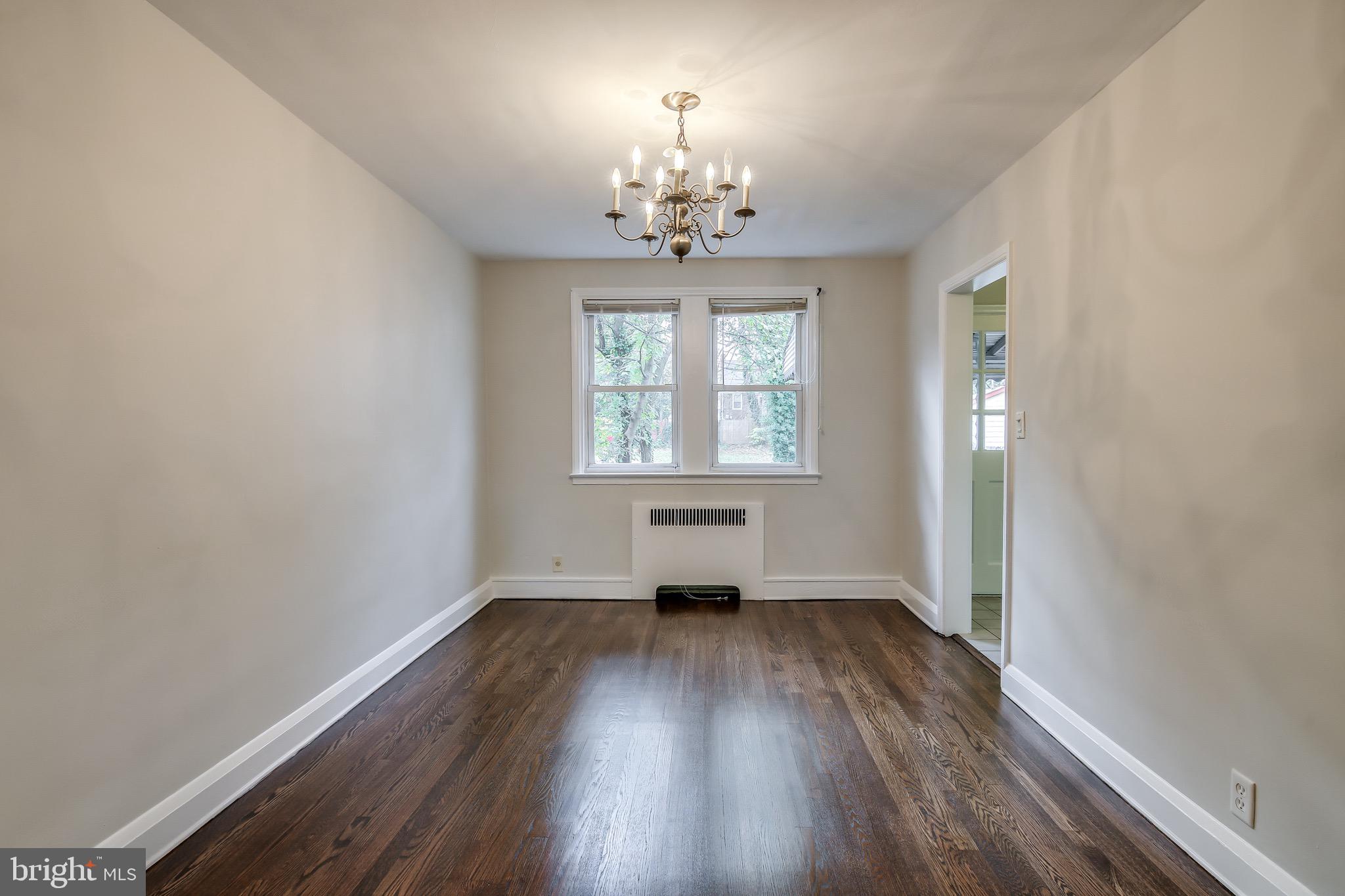 134 Cherrydell Road Baltimore, MD 21228 - Photo 10 of 36 an empty room with wooden floor chandelier and windows