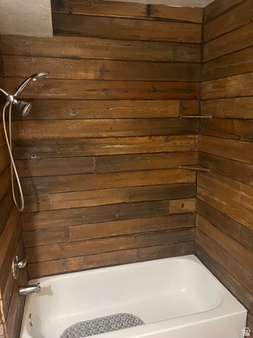1175 Canyon Road, Unit A 5 Ogden, UT 84404 - Photo 14 of 15 Bathtub and shower combination featuring wood-finish wall paneling, a chrome showerhead with a flexible hose, and coordinating chrome fixtures