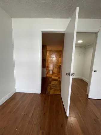 a view of a hallway with wooden floor and a living room