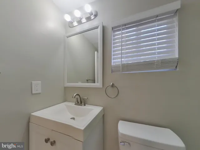 a bathroom with a toilet a sink a mirror a window and vanity
