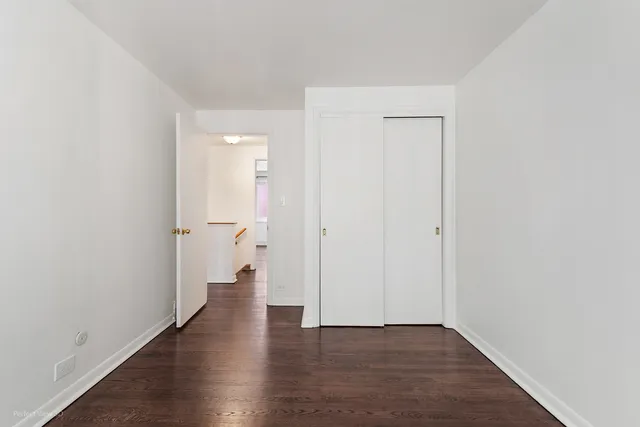 a view of an empty room with wooden floor and a large window