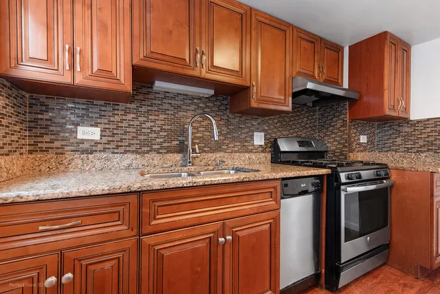 a kitchen with stainless steel appliances granite countertop a sink a stove cabinets and a counter top space