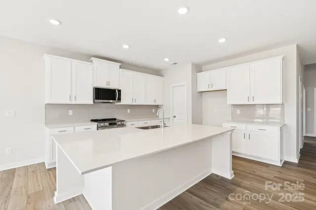 a kitchen with stainless steel appliances a white stove top oven sink and cabinets