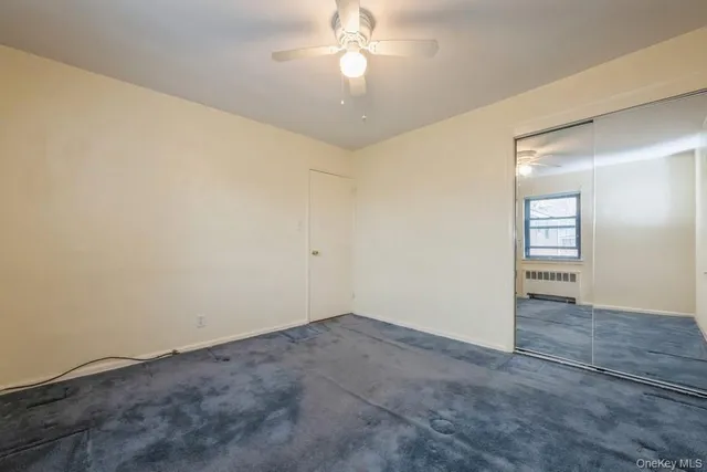 an empty room with closet and a chandelier fan