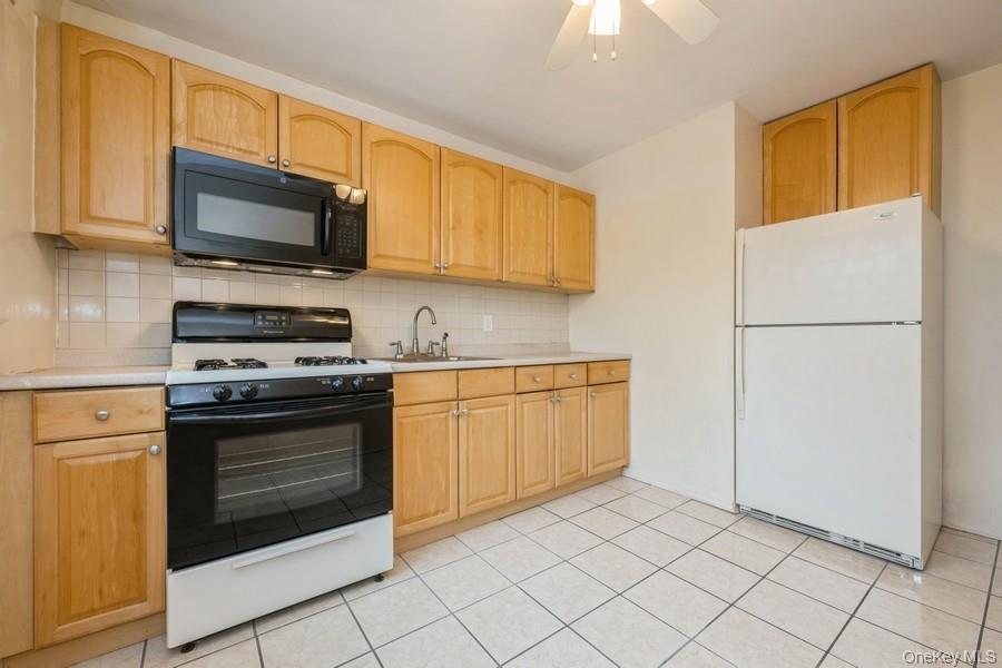 73-21 220th Street, Unit 139B2 Queens, NY 11364 - Photo 10 of 35 a kitchen with stainless steel appliances granite countertop a stove a sink and a microwave