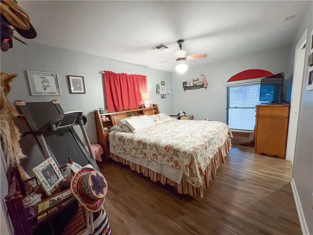 a bedroom with a bed and dresser with wooden floor