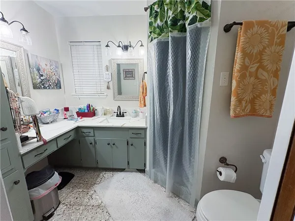 a bathroom with a granite countertop sink toilet and shower