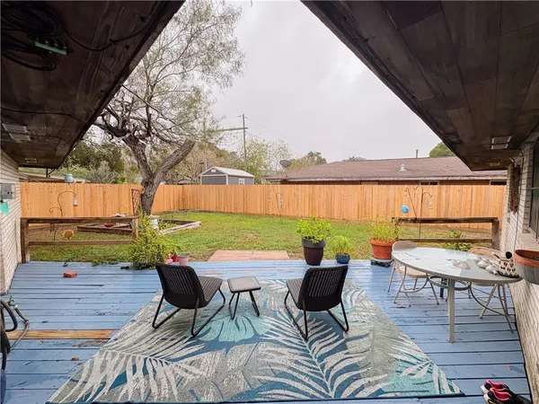 a backyard of a house with table and chairs under an umbrella