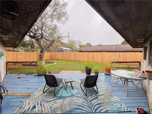 a backyard of a house with table and chairs under an umbrella