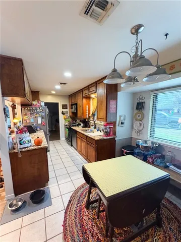 a room with stainless steel appliances kitchen island granite countertop a stove a sink and a dining table