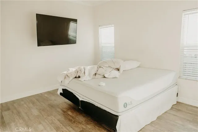 a white bed sitting in a bedroom next to a flat screen tv