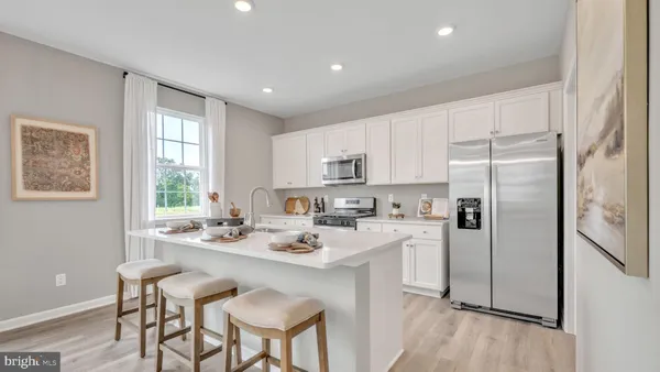 a kitchen with a refrigerator a sink dishwasher and white cabinets with wooden floor