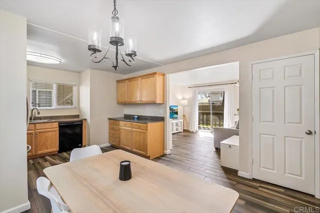 a kitchen with stainless steel appliances granite countertop a sink dishwasher a stove top oven a dining table and chairs with wooden floor