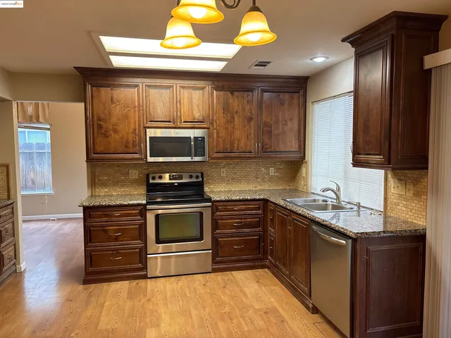 a kitchen with stainless steel appliances granite countertop a stove a microwave and a sink