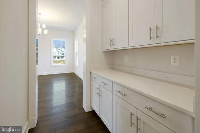 a kitchen with white cabinets and wooden floor