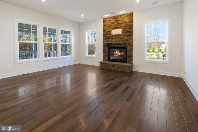 an empty room with wooden floor fireplace and windows