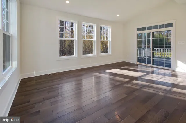 a view of an empty room with wooden floor and windows