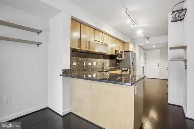 a kitchen with stainless steel appliances granite countertop a refrigerator a stove and a sink with wooden floor