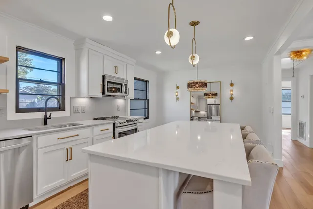 a very nice looking kitchen with granite countertop a stove a sink a microwave and dining table