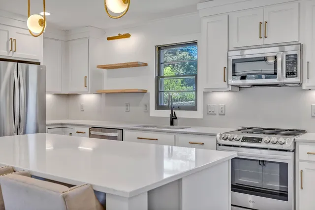 a kitchen with stainless steel appliances granite countertop a sink a stove and a microwave