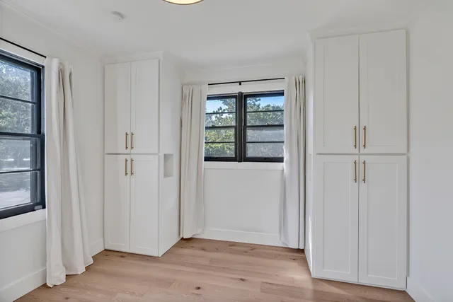 an empty room with wooden floor cabinet and windows