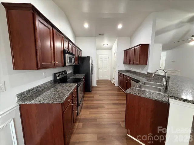a kitchen with stainless steel appliances granite countertop a sink stove microwave and refrigerator