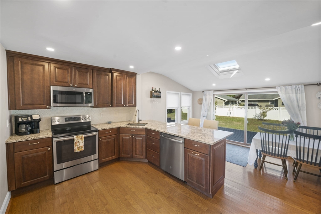 7 Rainbow Terrace Danvers, MA 01923 - Photo 10 of 33 a kitchen with stainless steel appliances granite countertop wooden cabinets a sink a stove a dining table and chairs
