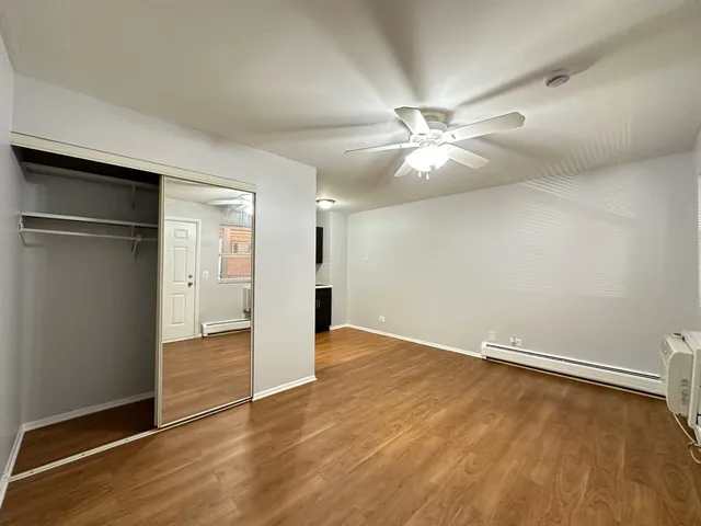 an empty room with wooden floor and a ceiling fan