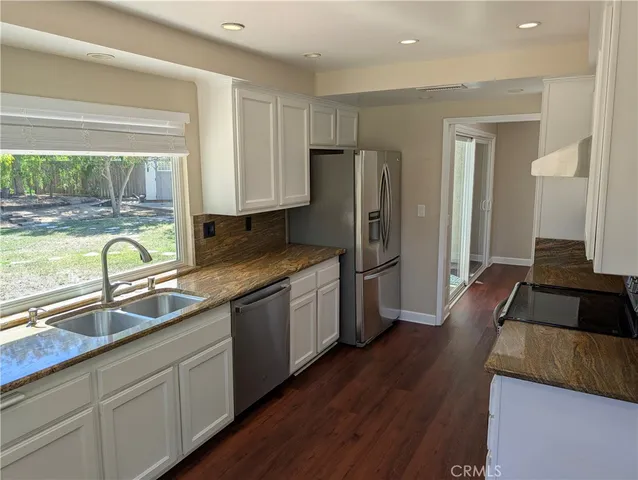 a kitchen with granite countertop a refrigerator a sink and wooden cabinets