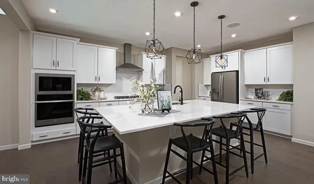a kitchen with stainless steel appliances kitchen island granite countertop a dining table chairs and white cabinets