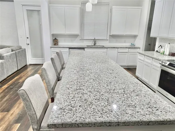 a kitchen with a sink a stove top oven and white cabinets