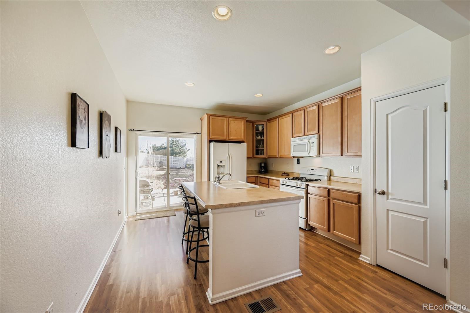 4712 Sandy Ridge Avenue Firestone, CO 80504 - Photo 12 of 29 a kitchen with a refrigerator a sink dishwasher and a stove with wooden floor