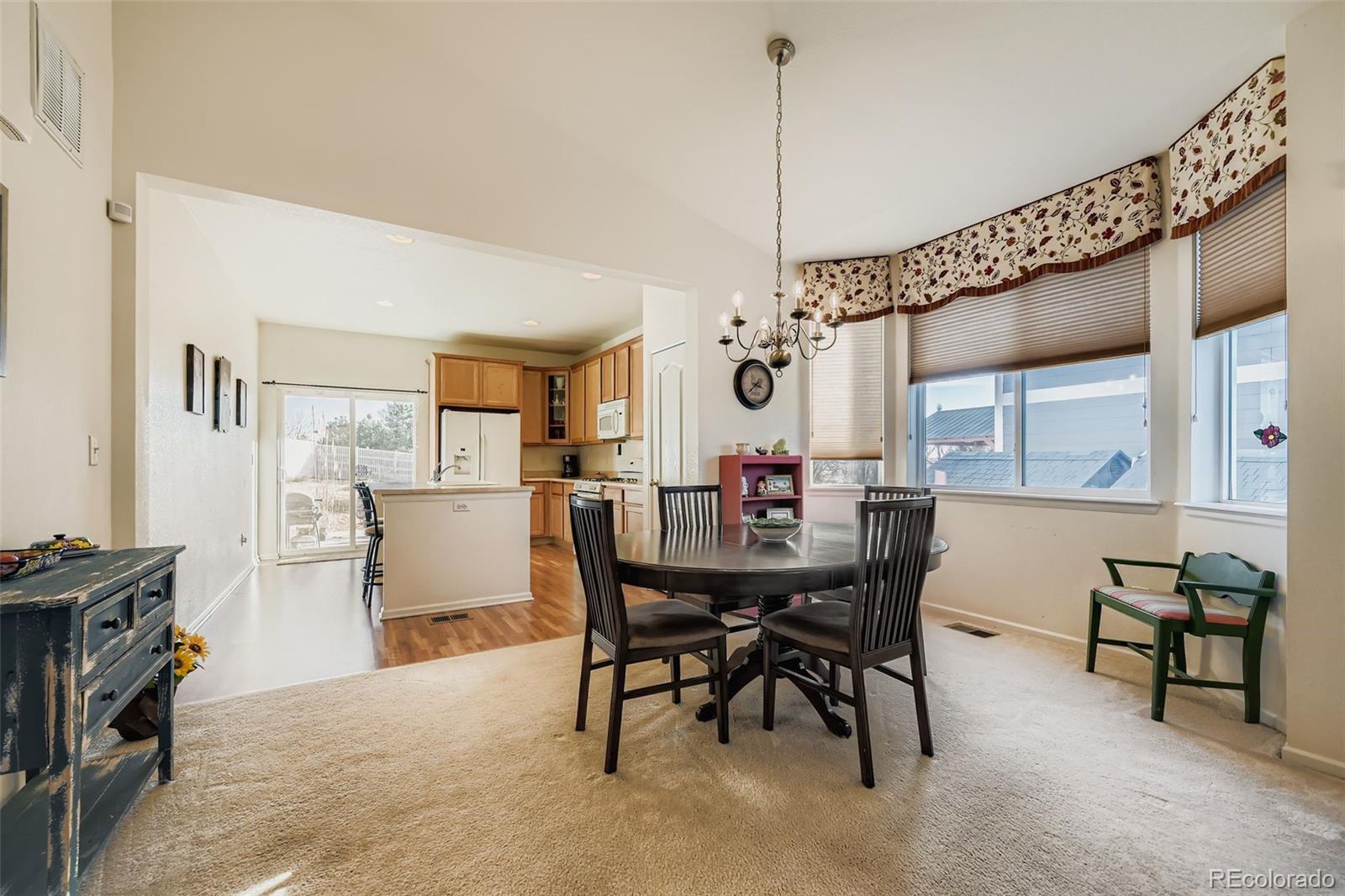 4712 Sandy Ridge Avenue Firestone, CO 80504 - Photo 13 of 29 a view of a dining room and livingroom with furniture wooden floor a rug a painting and a chandelier