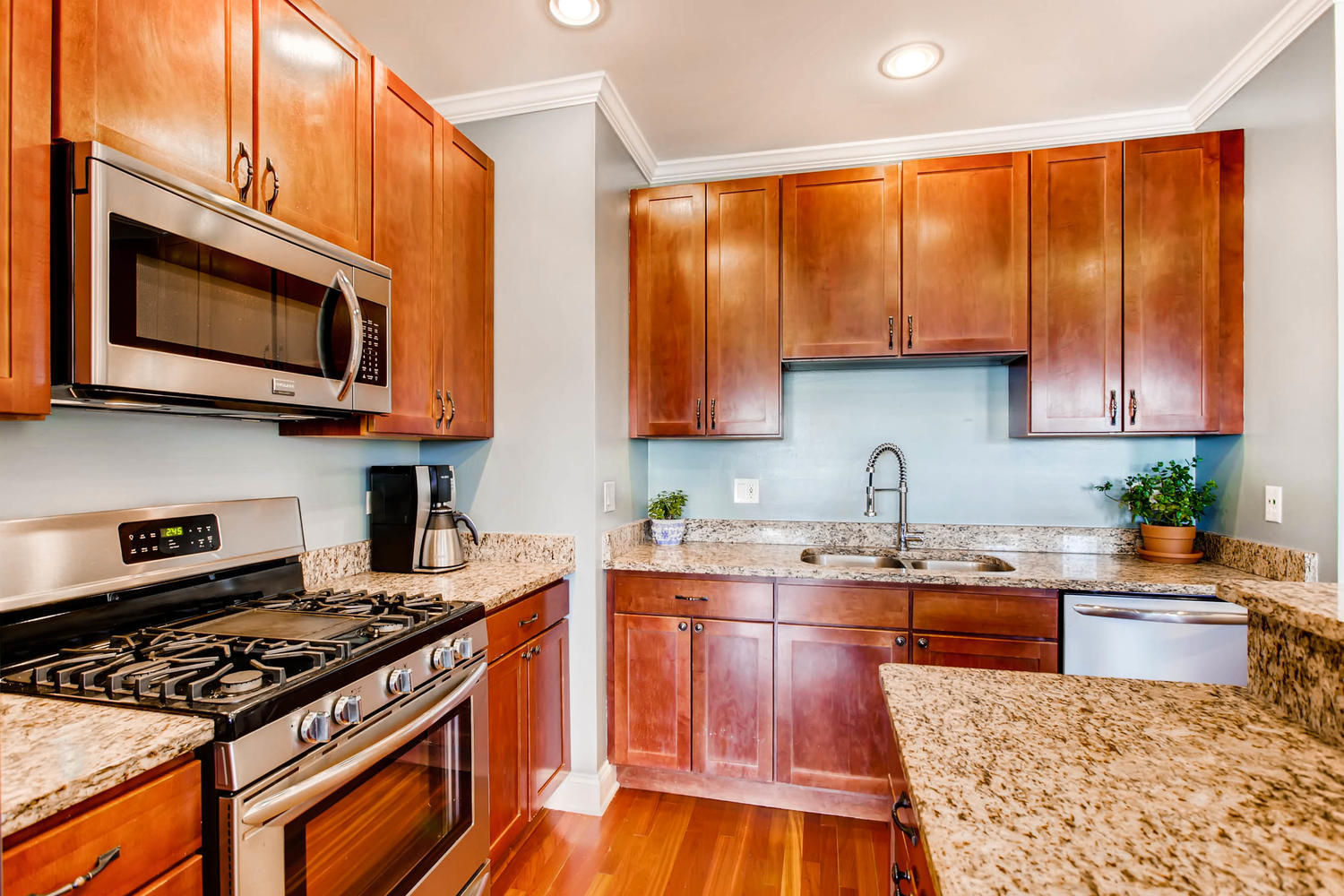 1242 West Pratt Boulevard, Unit 3F Chicago, IL 60626 - Photo 11 of 30 a kitchen with stainless steel appliances granite countertop a stove top oven a sink dishwasher and microwave with wooden floor