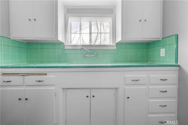 a view of a kitchen with white cabinets and a window