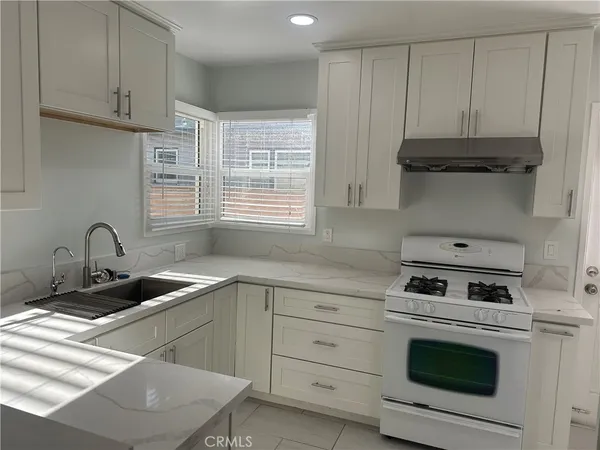 a kitchen with granite countertop a sink a stove and cabinets