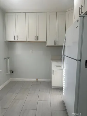 a kitchen with white cabinets and a refrigerator